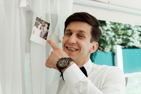 handsome stylish groom looking at first old photo with his bride long time ago, emotional fun momentの写真素材