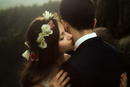 luxury happy bride and stylish groom kissing on background of  view of sunny rocks in amazing mountainsの写真素材