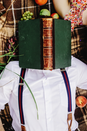 beautiful happy bride and stylish retro groom, having fun with books and relaxing, picnic in sunny meadowの写真素材