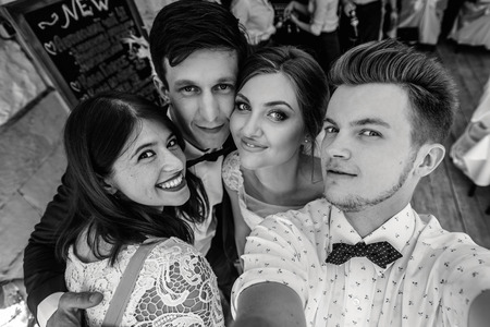 stylish happy guests and bride and groom having funny group selfie photos on the sunny day
