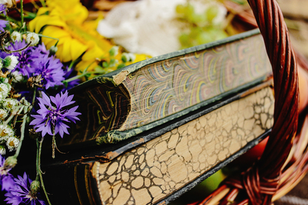 beautiful picnic wicker basket with colorful bouquet fruits and books on tweed plaid, close up, relaxing timeの写真素材