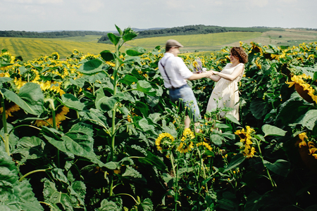 beautiful gorgeous bride and stylish handsome groom, joyful rustic couple in a sunflower fieldの写真素材