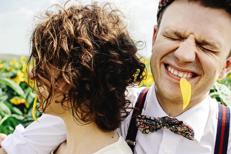 beautiful gorgeous bride and stylish handsome groom, rustic couple having fun in a sunflower field