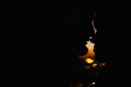 silhouette of happy couple looking at each other and touching with gentle on background of sunset sky and city lightsの写真素材