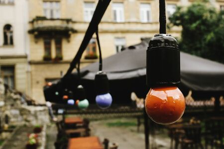 retro beautiful lamp lights on garland at cafe terrace in the street in europe city holiday, space...