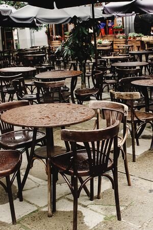 stylish wooden chairs and tables empty at rainy day on streets of europe cityの写真素材