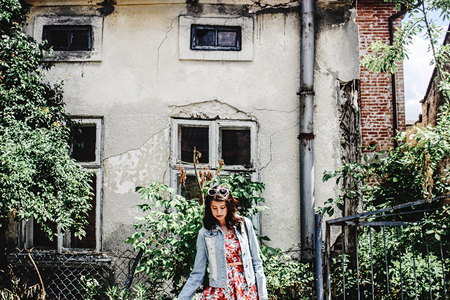 stylish brunette beautiful woman smiling in floral dress on the background of old buildingの写真素材