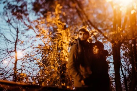 happy stylish couple hugging and holding hands with tender under yellow lantern  in night lights of the cityの写真素材