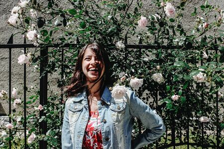 stylish brunette beautiful woman having fun and smiling in floral dress in the sunny streetの写真素材