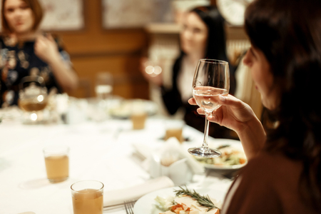hand of stylish woman holding glass of champagne and toasting at luxury restaurant, space for textの写真素材