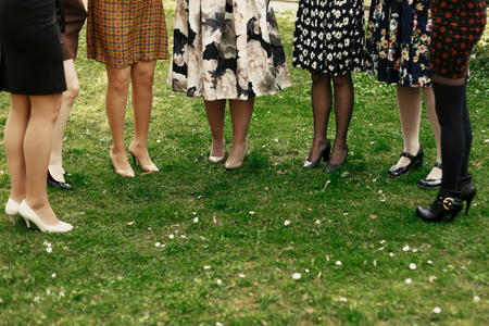 stylish elegant women showing legs at celebration in sunny park, gathering togetherの写真素材