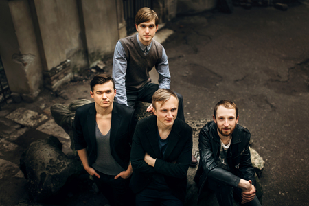 stylish handsome group of men standing and posing on the background of city streetの写真素材
