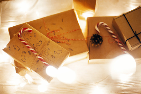 christmas presents flat lay in lights in evening festive room under christmas tree in warm illumination on eve. space for text. modern craft gifts. merry christmas. happy new yearの写真素材