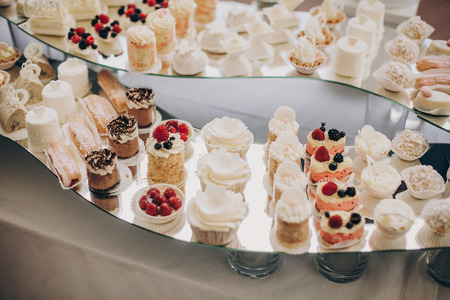stylish pink candy bar table with delicious cakes,cookies,cupcakes with fruits in pink and white colors. luxury catering in restaurant. modern wedding reception. sweet tableの写真素材