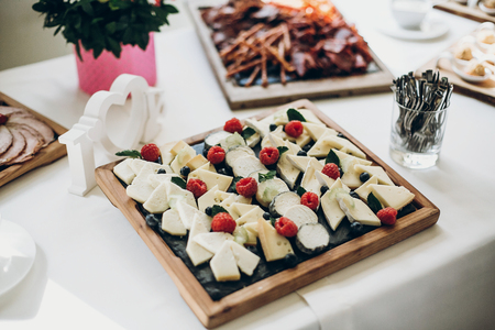delicious table with different cheese at wedding reception in restaurant. cheese with berries on plate, luxury cateringの写真素材