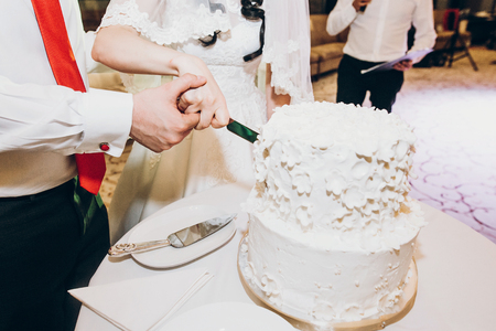 bride and groom cutting delicious wedding cake at wedding reception in restaurant, luxury cateringの写真素材