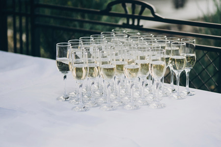 stylish champagne glasses on wedding table. luxury drinks for celebration, reception outdoors. catering. christmas feastの写真素材