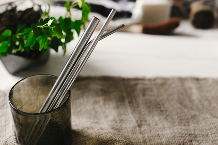 eco natural metallic straws in green glass on rustic background with greenery. sustainable lifestyle concept. zero waste, plastic free items. stop plastic pollution.の写真素材