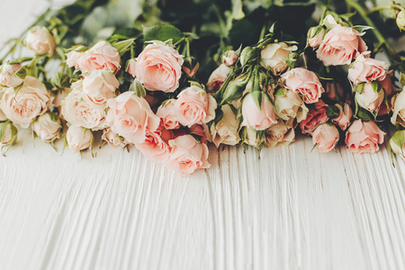Pink small roses on wooden background, space for text. Floral greeting card mockup. Wedding invitation,happy mother day or Valentine day concept. Hello spring. Tender Flower borderの写真素材