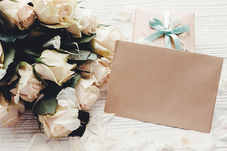 White roses with empty card and gift box on wooden background, space for text. Floral greeting card mockup. Wedding invitation,happy mother day concept. Valentine dayの写真素材