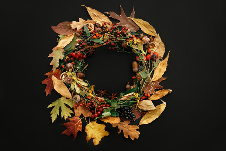 Autumn Wreath Flat Lay. Fall leaves circle with berries, nuts, acorns, flowers,herbs on black background top view. Seasons greetings. Space for text. Autumn Creative compositionの写真素材