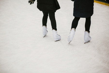 Skaters skating on iceskating ring in european city center in winter holidays.  Kids playing on white ice skating ring, healthy activity. Child legs in white skatesの写真素材