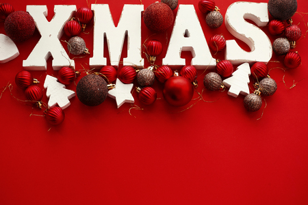 Merry Christmas. Xmas wooden word with red and gold baubles ornaments on red  bright paper, flat lay. Season's greeting card. Copy space. Stylish traditional holiday image. Christmas textの写真素材