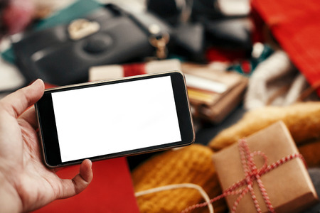 Christmas shopping and sale. Hand holding phone with empty screen on background of credit cards,money, wallet, bags, clothes, gifts, jewelry. Space for text. Advertising app. Black Fridayの写真素材