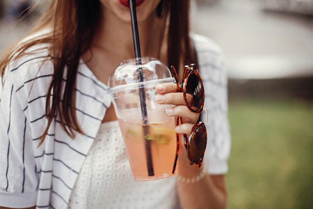 Ban single use plastic. Happy hipster girl  in retro dress, holding plastic cup and straw. Beautiful...