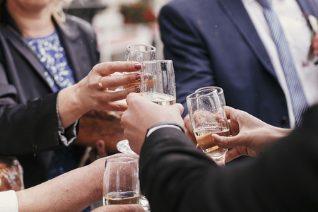 Group of people cheering and toasting with champagne at wedding reception. Corporate businessman...