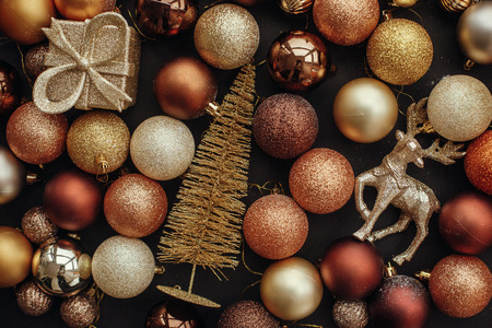 Christmas gold gift box, tree, reindeer and glitter baubles on stylish black background. Modern Christmas flat lay image. Seasons greetings card. Merry Christmas and Happy New Yearの写真素材