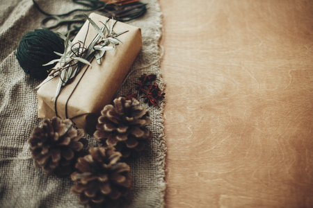 Stylish rustic christmas gift box with green branch and fir branches, anise, pine cones, cinnamon on rustic wooden background. Simple eco present. Atmospheric mood. Space textの写真素材