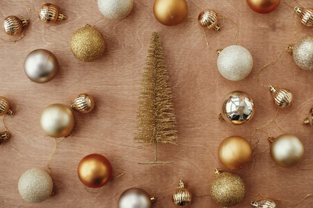 Christmas golden glitter tree and shiny baubles and balls on rustic background, flat lay. Modern gold decorations and present. Seasons greetings. Merry Christmas. Happy holidaysの写真素材