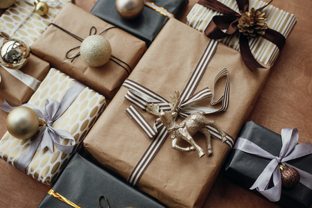 Merry Christmas. Christmas stylish gift boxes with glitter reindeer,baubles, ornaments on rustic wooden background. Modern black and gold presents. Seasons greetings. Happy holidaysの写真素材