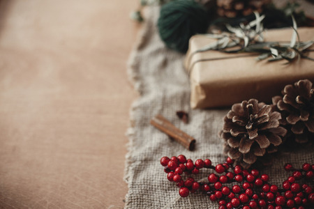 Merry Christmas concept, atmospheric rustic image. Pine cones and red berries at rustic gift box with green branch,anise, cinnamon on rustic wooden background. Space for textの写真素材