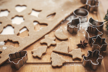 Making christmas gingerbread cookies. Tree and stars dough, metal cutters on rustic table with  cinnamon ,anise, cones, christmas decorations. Atmospheric stylish imageの写真素材