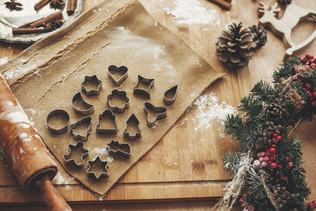 Making christmas gingerbread cookies. Dough with metal cutters on rustic table with wooden rolling pin, cinnamon ,anise, cones, christmas decorations. Atmospheric stylish imageの写真素材