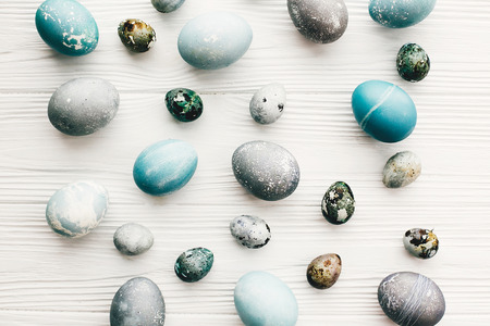 Stylish easter eggs on white wooden background, flat lay. Modern easter eggs painted with natural dye in blue and grey marble color. Happy Easter pattern, greeting cardの写真素材