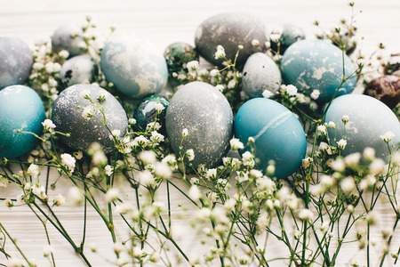 Stylish easter eggs with spring flowers on white wooden background. Modern easter eggs painted with natural dye in blue, grey  marble color. Happy Easter, greeting cardの写真素材
