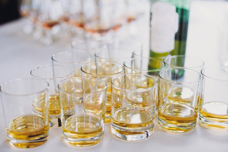 Whiskey row on table party at wedding reception. Whisky in glasses at alcohol bar. Christmas and New Year feast. Celebrations and party concept. Alcoholic drinksの写真素材