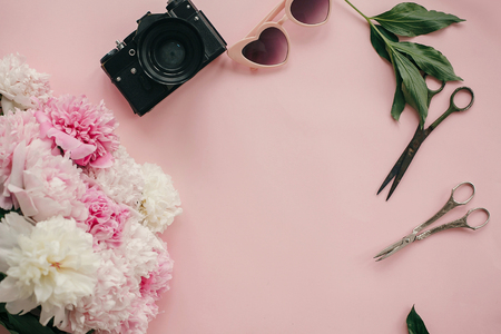 White and pink peonies, scissors, photo camera and sunglasses on pastel pink paper. Feminine flat lay with copy space. Hello spring image. Summer vacation. International Women's Dayの写真素材