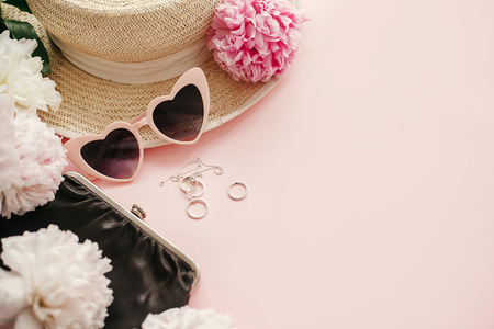 Stylish girly pink retro sunglasses,peonies, jewelry, hat, purse on pastel pink paper with copy space.  Hello spring concept. Summer vacation. International Women's Dayの写真素材