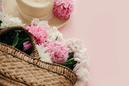 Straw hat and rustic bag with white and pink peonies on pastel pink paper.  Hello spring image with copy space. Summer vacation concept. International Women's Day. Happy mothers dayの写真素材