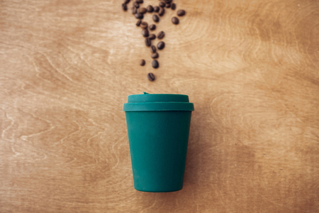 Stylish reusable eco coffee cup on wooden background with roasted coffee beans. Ban single use plastic. Zero waste concept, flat lay. Sustainable lifestyle. Natural bamboo cupの写真素材