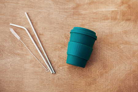Stylish reusable eco coffee cup and metallic steel straws on wooden background, flat lay. Ban single use plastic, zero waste concept.Natural bamboo cup and reusable straws. Sustainable lifestyleの写真素材