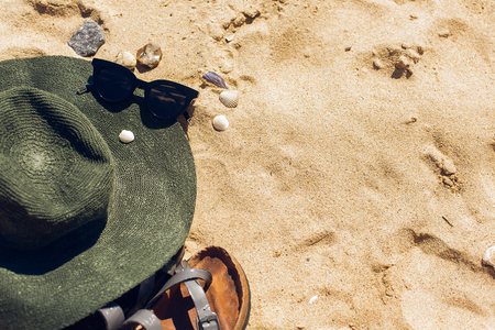 Stylish sunglasses, hat, sandals on sandy beach with seashells, top view with copy space. Summer vacation and travel concept. Summer accessory and essentialsの写真素材