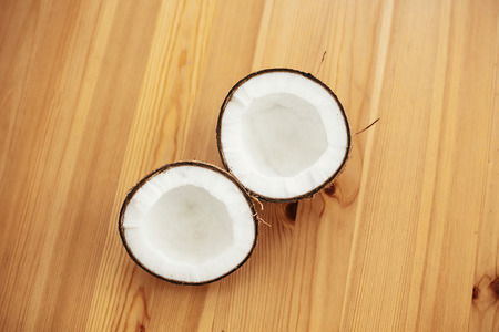 Halved coconut on wooden table, flat lay. Hello summer vacation concept. Space for text. Tropical background with coconut. Delicious nut, refreshing drink and oil source, tasty milkの写真素材