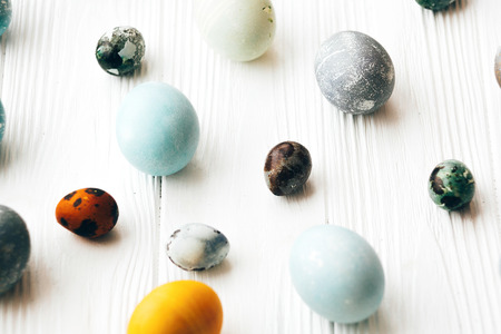 Stylish Easter eggs on white wooden background. Modern easter eggs painted with natural dye in...