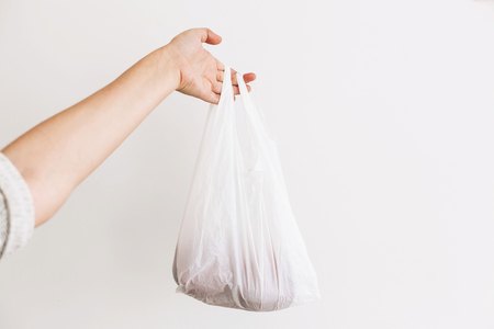 Ban single use plastic. Woman holding in hand groceries in plastic polyethylene bag. Zero Waste shopping concept.  Reuse, reduce, recycle, refuse. Choose eco natural bagsの写真素材