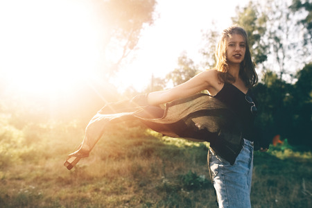 Stylish hipster girl having fun in sunny park in amazing sunbeams, atmospheric moment. Fashionable cool woman dancing in evening light. Selective focus. Retro effect. Creative image. Space textの写真素材